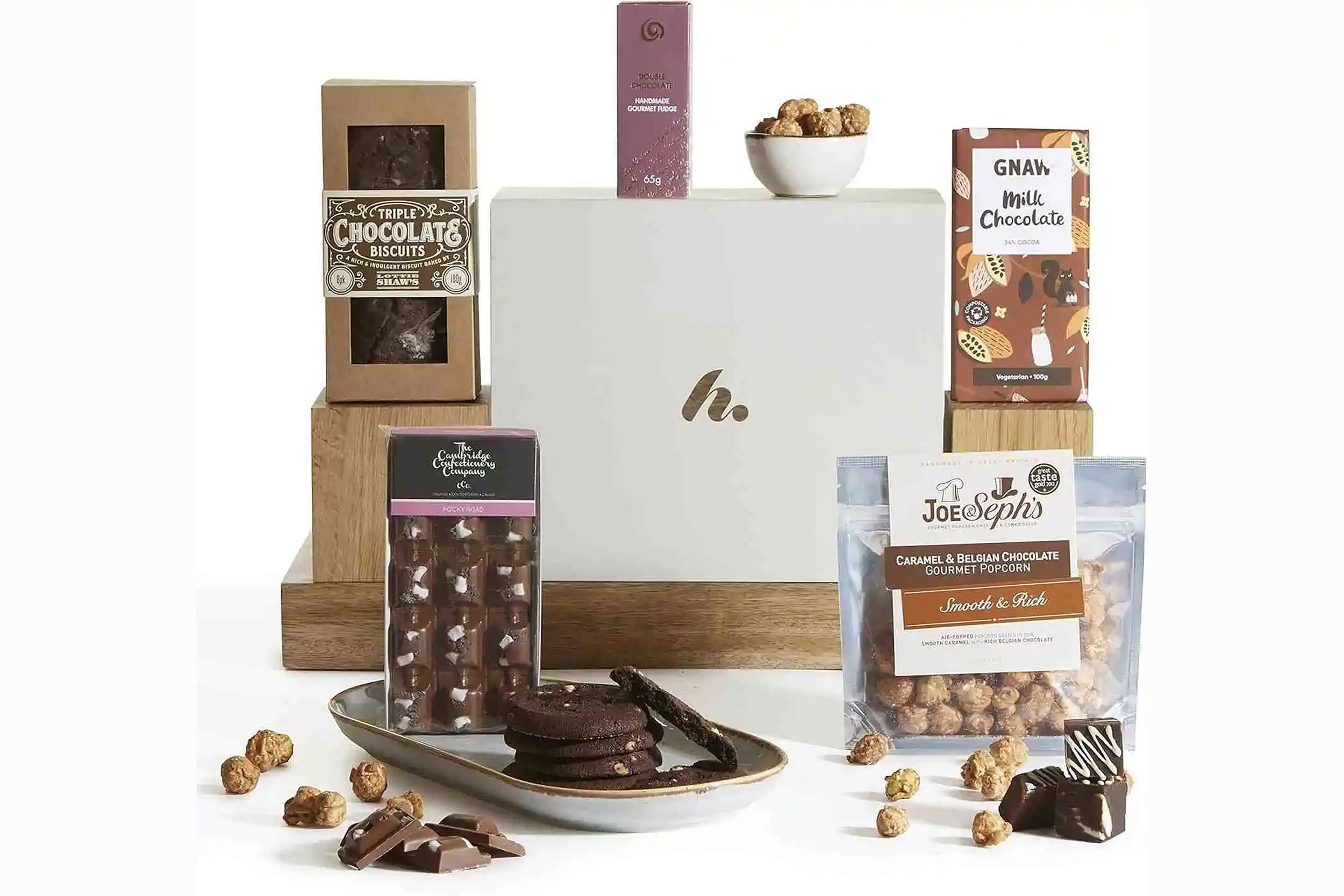 A luxury chocolate hamper displaying dark biscuits, popcorn, and a treat box.