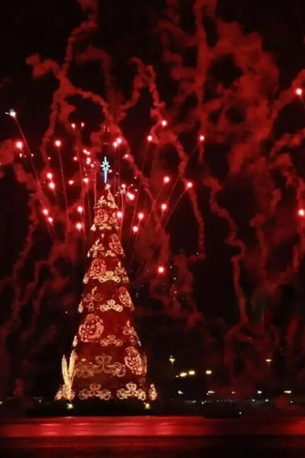 A massive illuminated red and gold holiday tree glowing during a New Year celebration.