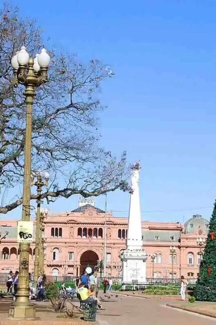 The historic Casa Rosada and white obelisk monument under a blue sky in Buenos Aires.