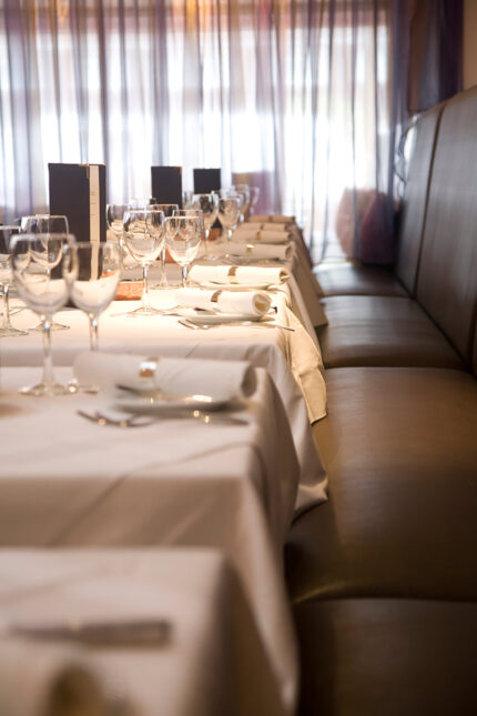 Elegant fine dining table setting with white linen and polished wine glasses at Zari.