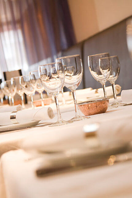 Close-up of an elegant restaurant table setting with polished wine glasses and linen.