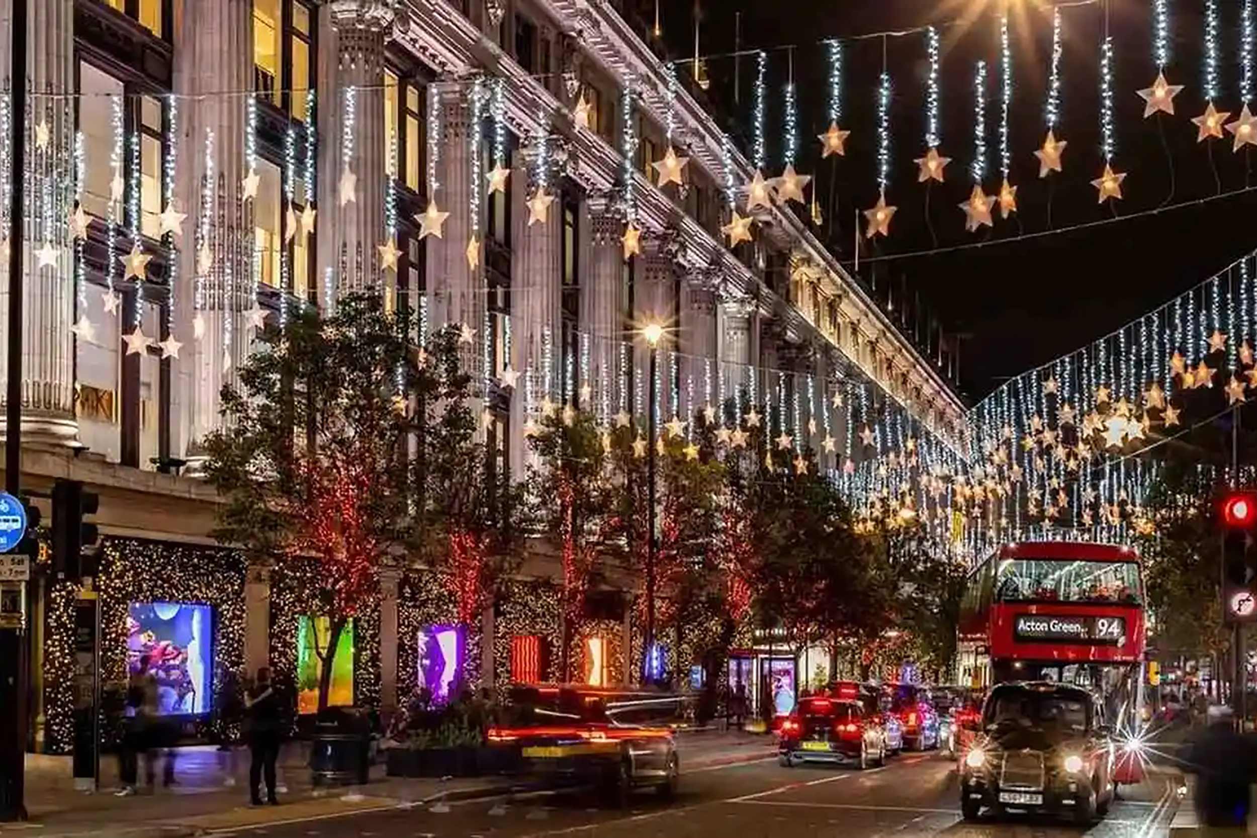 Festive holiday star lights hanging over a bustling city street during New Year's Eve.