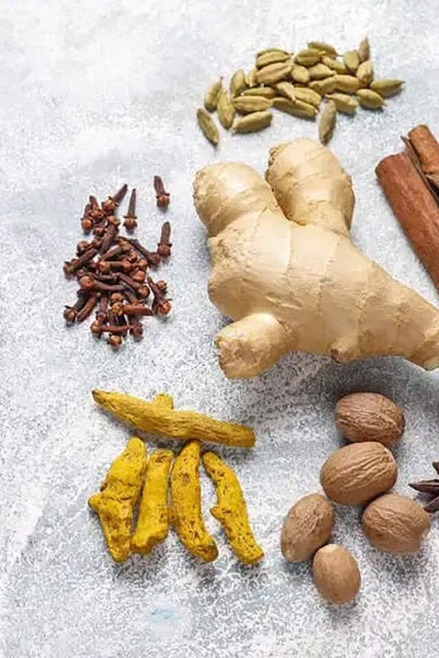 Fresh ginger, garlic cloves, and bright turmeric powder used for healthy cooking at Zari.