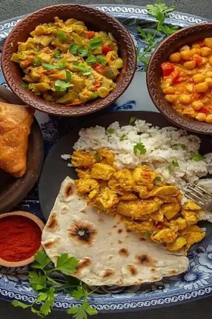 A balanced Indian meal platter with rice, flatbread, chicken, and healthy chickpea curry.