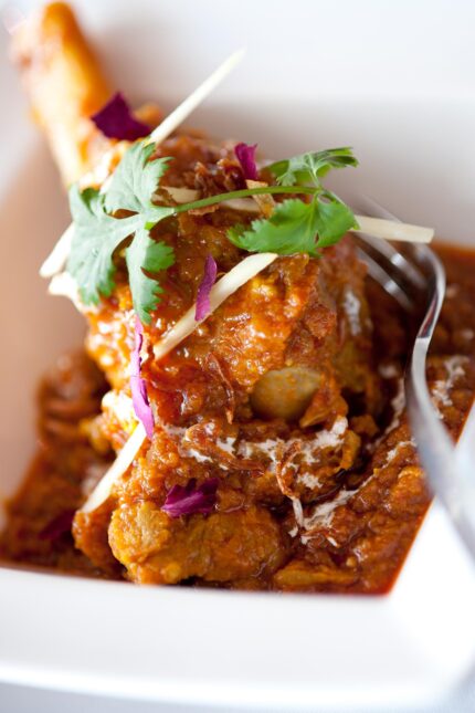 A rich, aromatic Indian chicken curry garnished with fresh ginger and coriander.