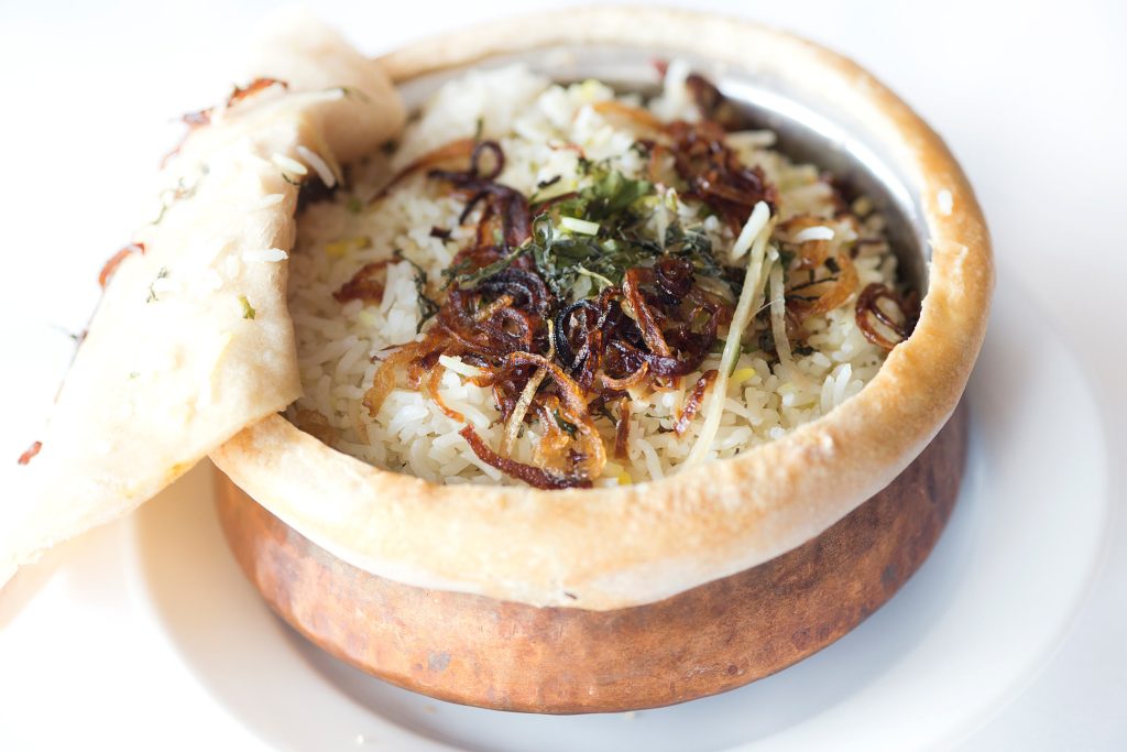 Authentic pot biryani topped with crispy fried onions and fresh mint leaves for a feast.