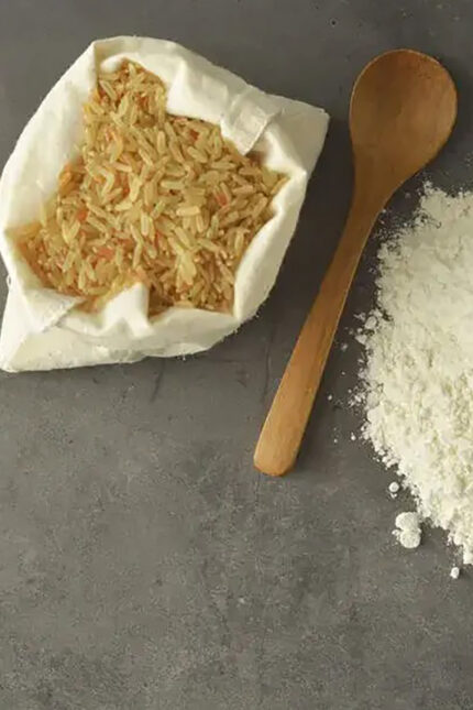 Raw brown rice in a sack with a wooden spoon and flour, highlighting healthy grains.