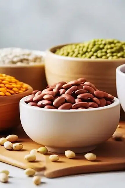 Bowls of protein-rich red kidney beans, green lentils, and split peas on a wooden board.