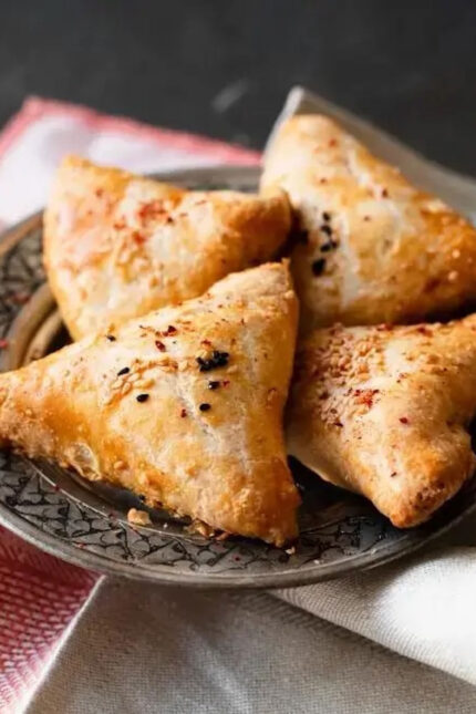 Three crispy golden samosas served fresh on a decorative plate at Zari Crawley.