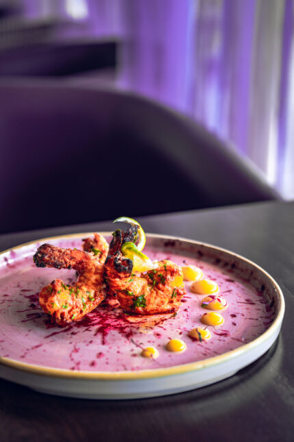 Tandoori king prawns elegantly served on a vibrant pink sauce swirl at Zari Crawley.