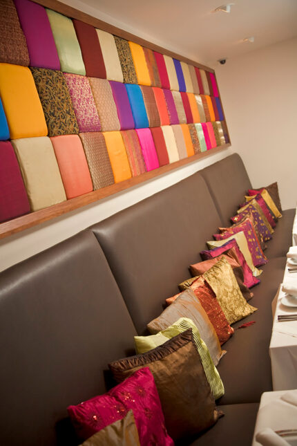 Comfortable leather banquette seating lined with colorful cushions at Zari Restaurant.