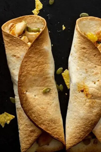 Two crispy cone-shaped masala dosas served upright on a modern dark plate.