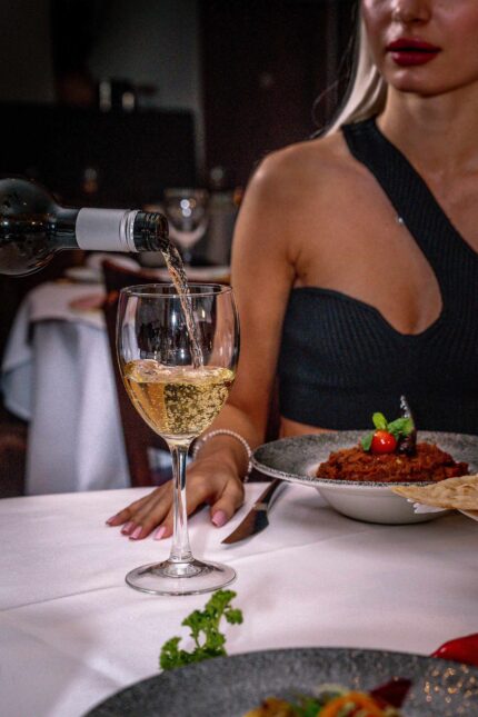 Pouring crisp white wine into a glass during a holiday group dinner celebration in Crawley.