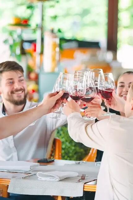 A smiling group of diners raising wine glasses for a celebratory toast at Zari Crawley.