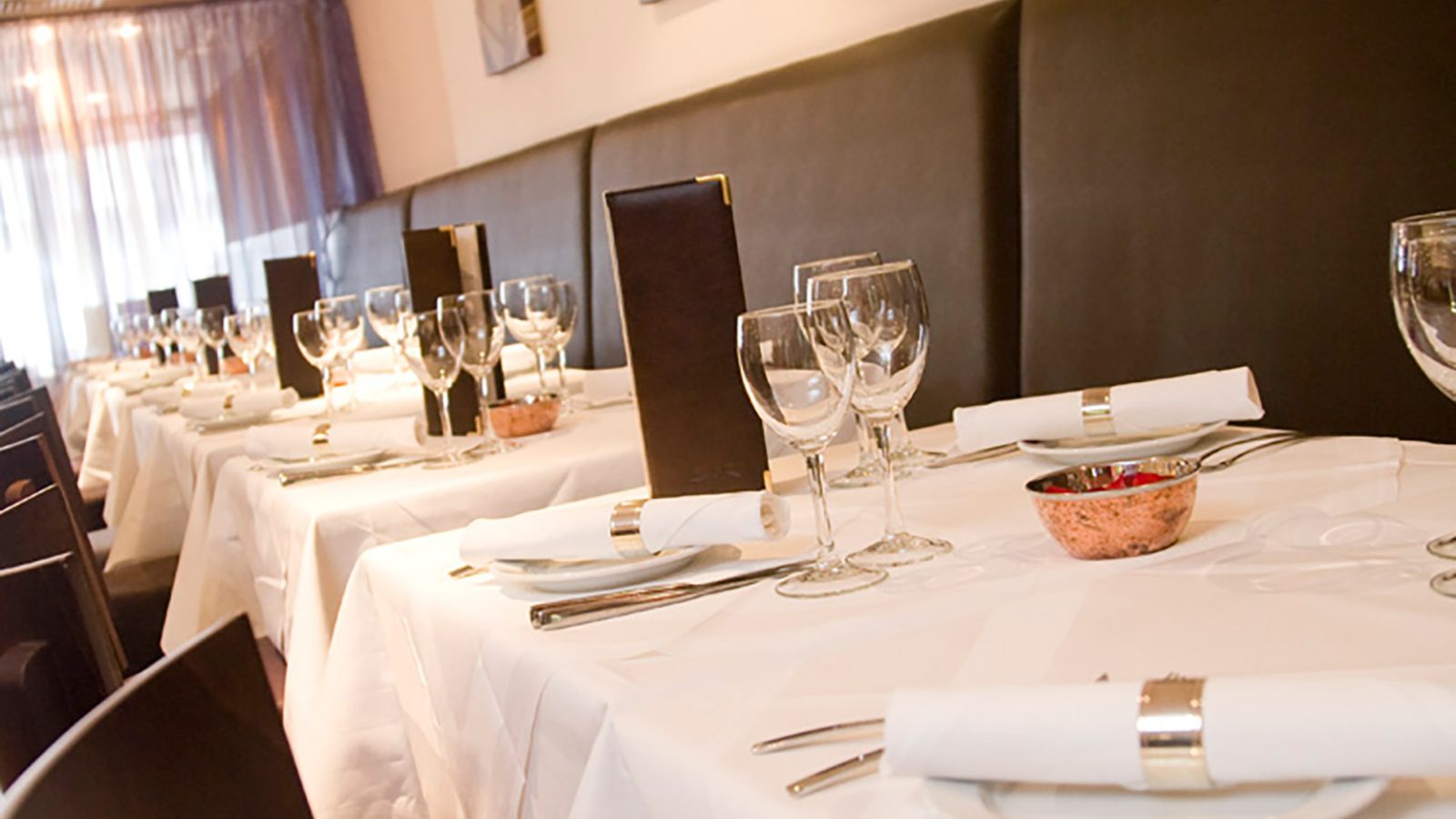 Private dining room with white tablecloths and brown chairs at Zari Restaurant.