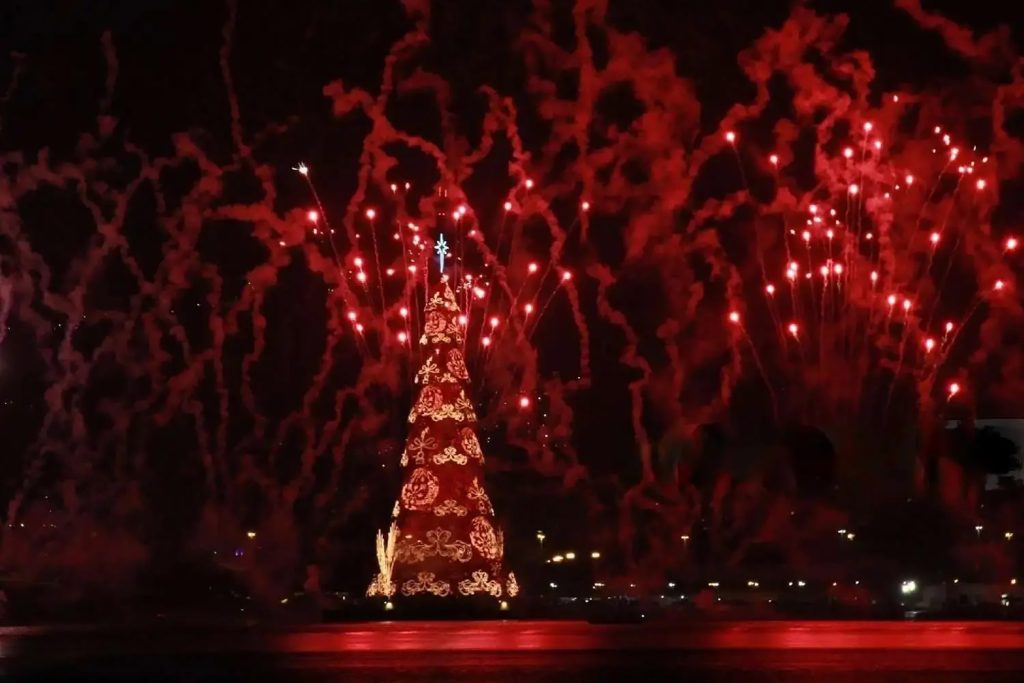 A massive illuminated red and gold holiday tree glowing during a New Year celebration.