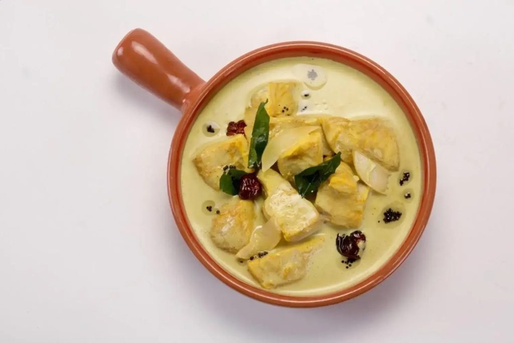 Aromatic South Indian Alleppey fish curry with coconut milk in a clay serving dish.