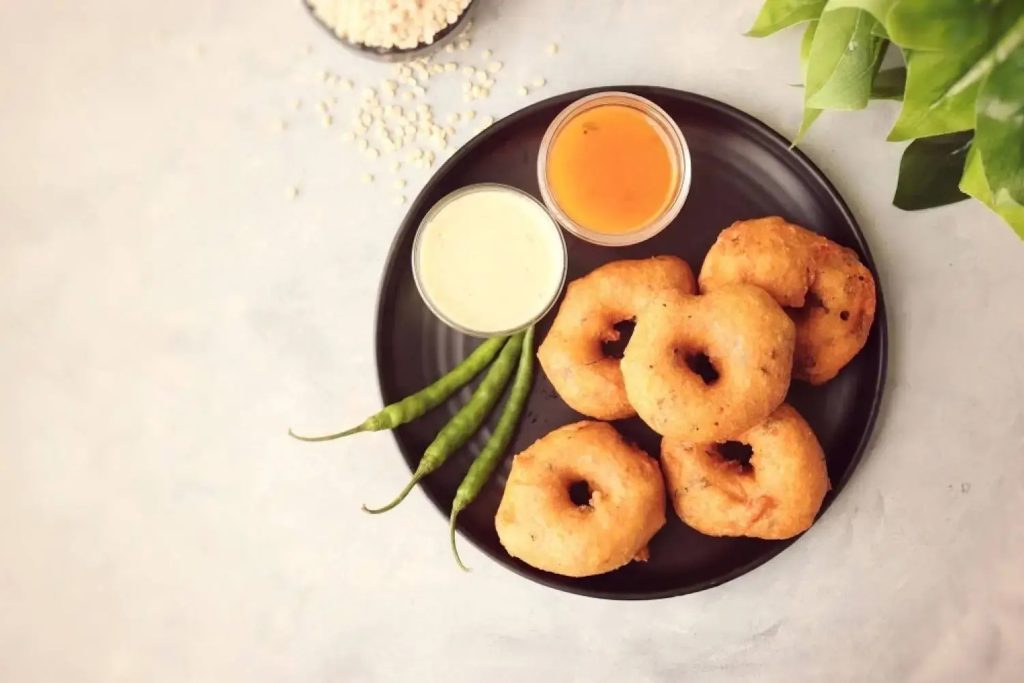 Crispy South Indian medu vada with dipping chutneys and green chillies at Zari Crawley.