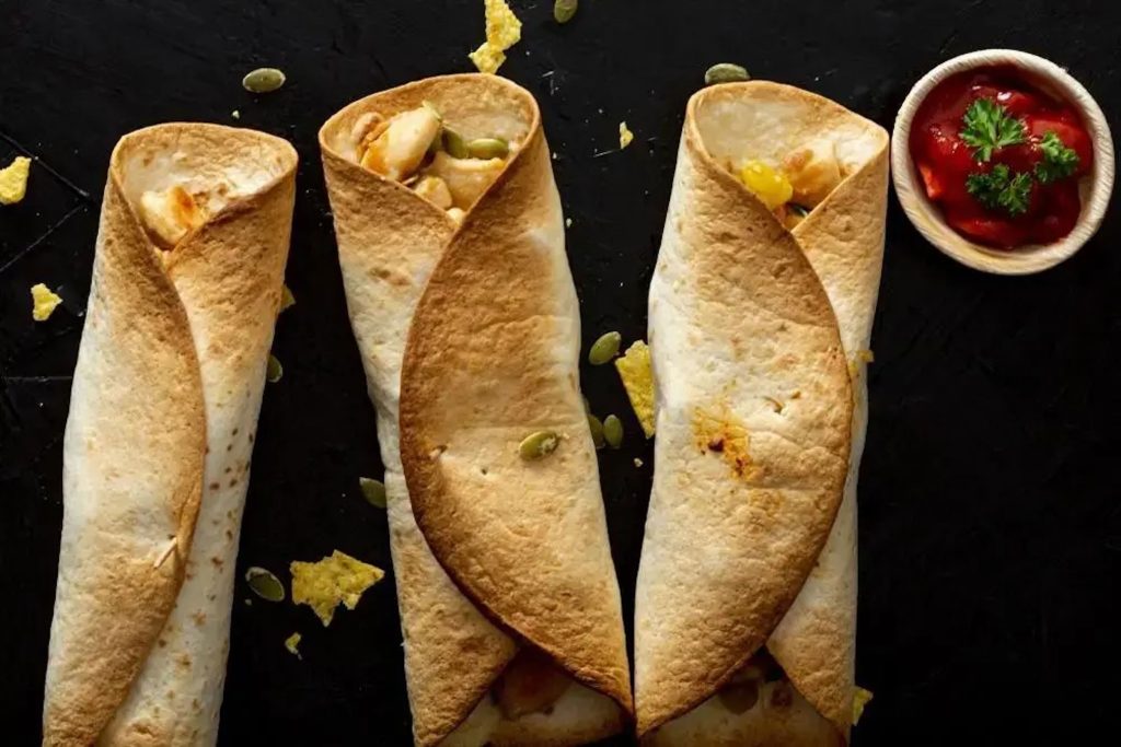 Two crispy cone-shaped masala dosas served upright on a modern dark plate.