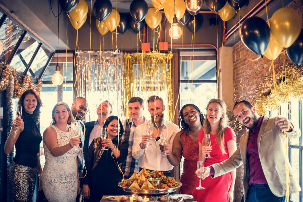 Guests raising champagne glasses beside a platter of samosas and onion bhajis